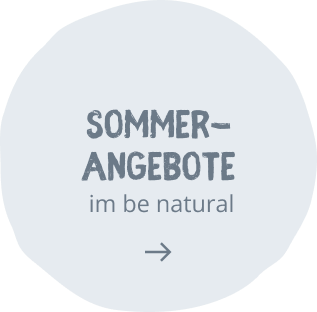 BE BIO Hotel be natural Sommerangebote Stoerer Round pale blue promo badge with the text 'SOMMER-ANGEBOTE' and 'im be natural' and a rightward arrow, signaling a summer offers CTA.